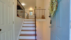 A staircase with wooden steps and black railings leading to a kitchen area. - Kiamesha Lake Home w/ Deck: 4 Mi to Resorts World! (Kiamesha Lake)
