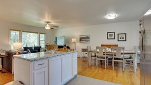 A modern kitchen with white cabinetry, a granite countertop, and a dining area with a wooden table and chairs. - Kiamesha Lake Home w/ Deck: 4 Mi to Resorts World! (Kiamesha Lake)
