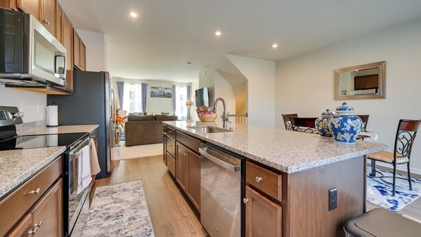 Una cocina moderna con encimeras de granito, electrodomésticos de acero inoxidable y muebles de madera.