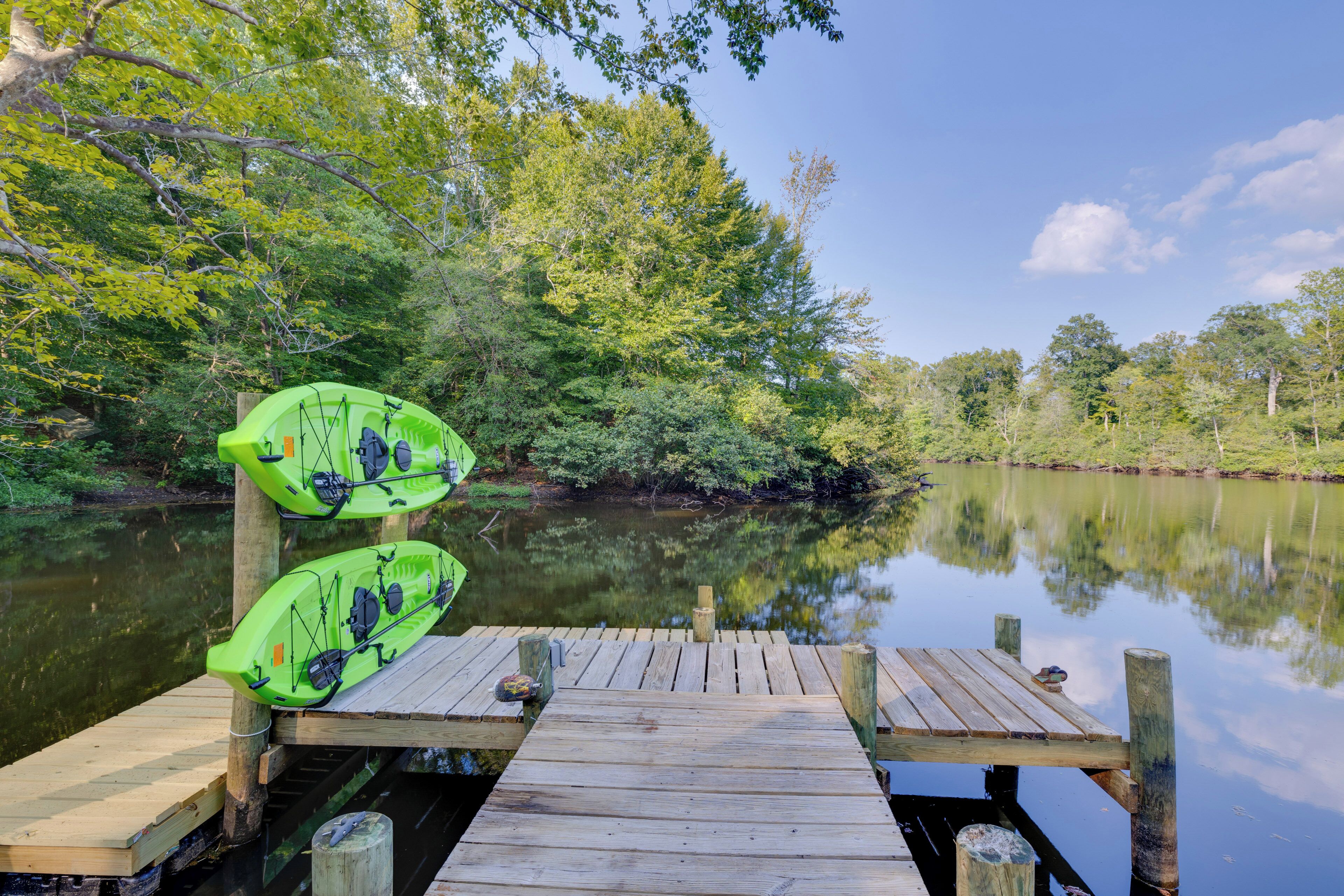 A wooden dock with two green kayaks.