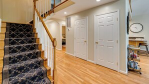 A staircase with patterned carpet leading to a landing, a wooden railing, and a wall-mounted clock. - Waterfront Hartfield Vacation Rental w/ Dock! (Hartfield)