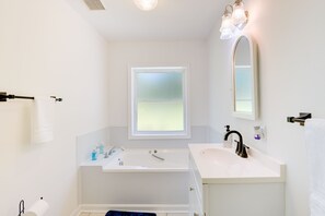 A modern bathroom with a bathtub, a sink, and a large mirror. - Sun-dappled Waterfront Home on Potomac River! (Scotland)