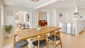A spacious kitchen with a wooden table and chairs, a built-in island, and a modern range hood. - Sun-dappled Waterfront Home on Potomac River! (Scotland)