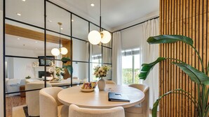 Un espace de salle à manger moderne avec une table ronde, des chaises blanches et un vase de fleurs.