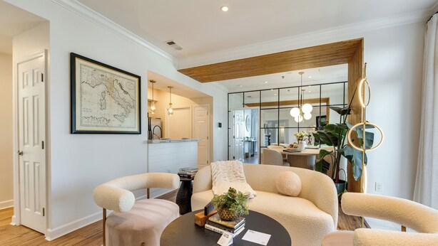 Un salon moderne avec un canapé, des fauteuils, une table basse et une carte accrochée au mur.