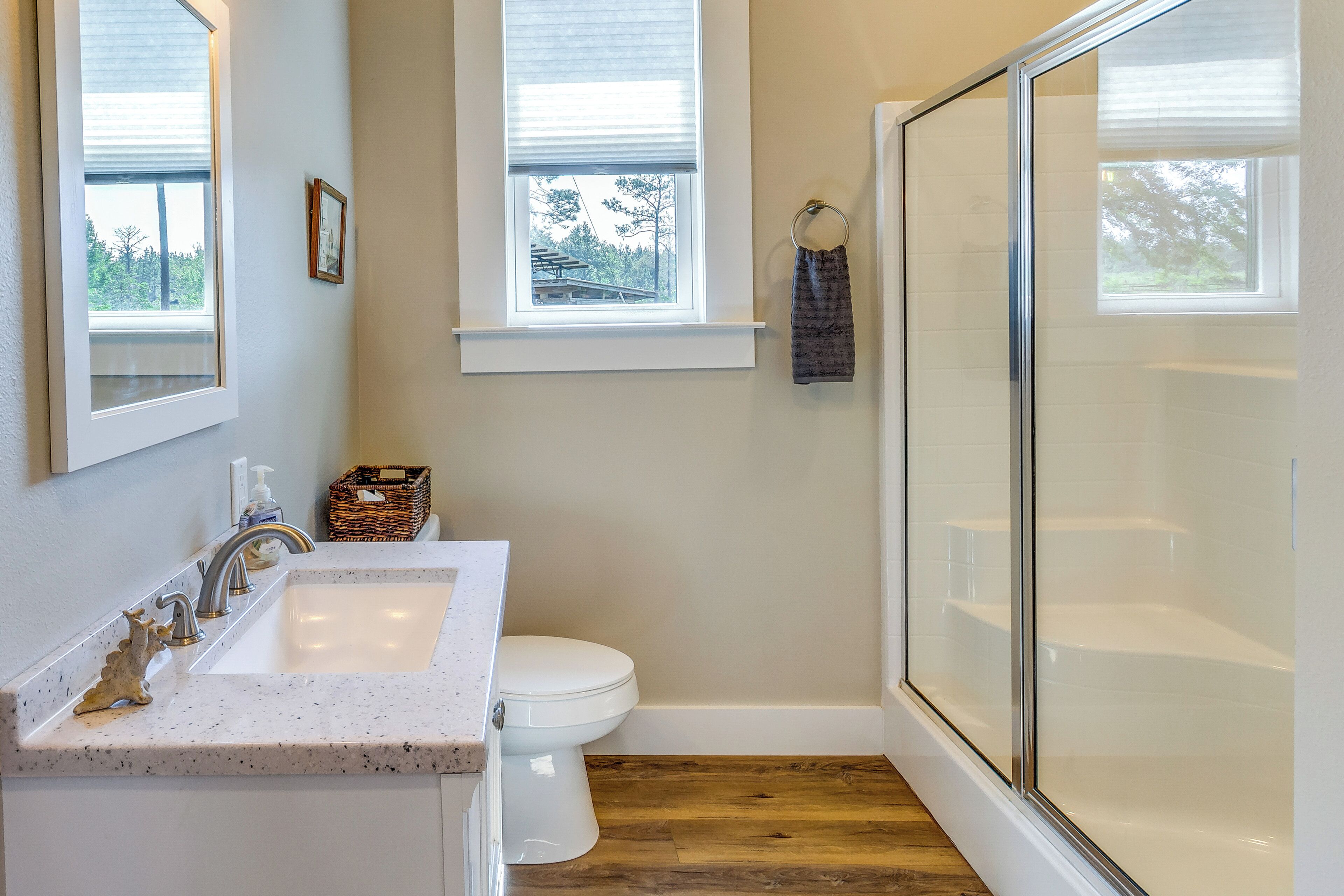 A bathroom with a white sink, toilet, and glass shower enclosure.