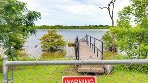 Un área cercada con un letrero de advertencia, un muelle de madera y un lago.
