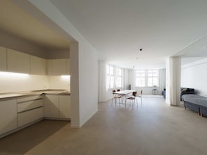 Een moderne, open woonruimte met keuken, eethoek en slaapkamer.