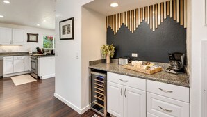 A modern kitchen with white cabinets, a built-in wine cooler, and a granite countertop. - Modern Meadow Vista Vacation Home w/ Spacious Deck (Meadow Vista)