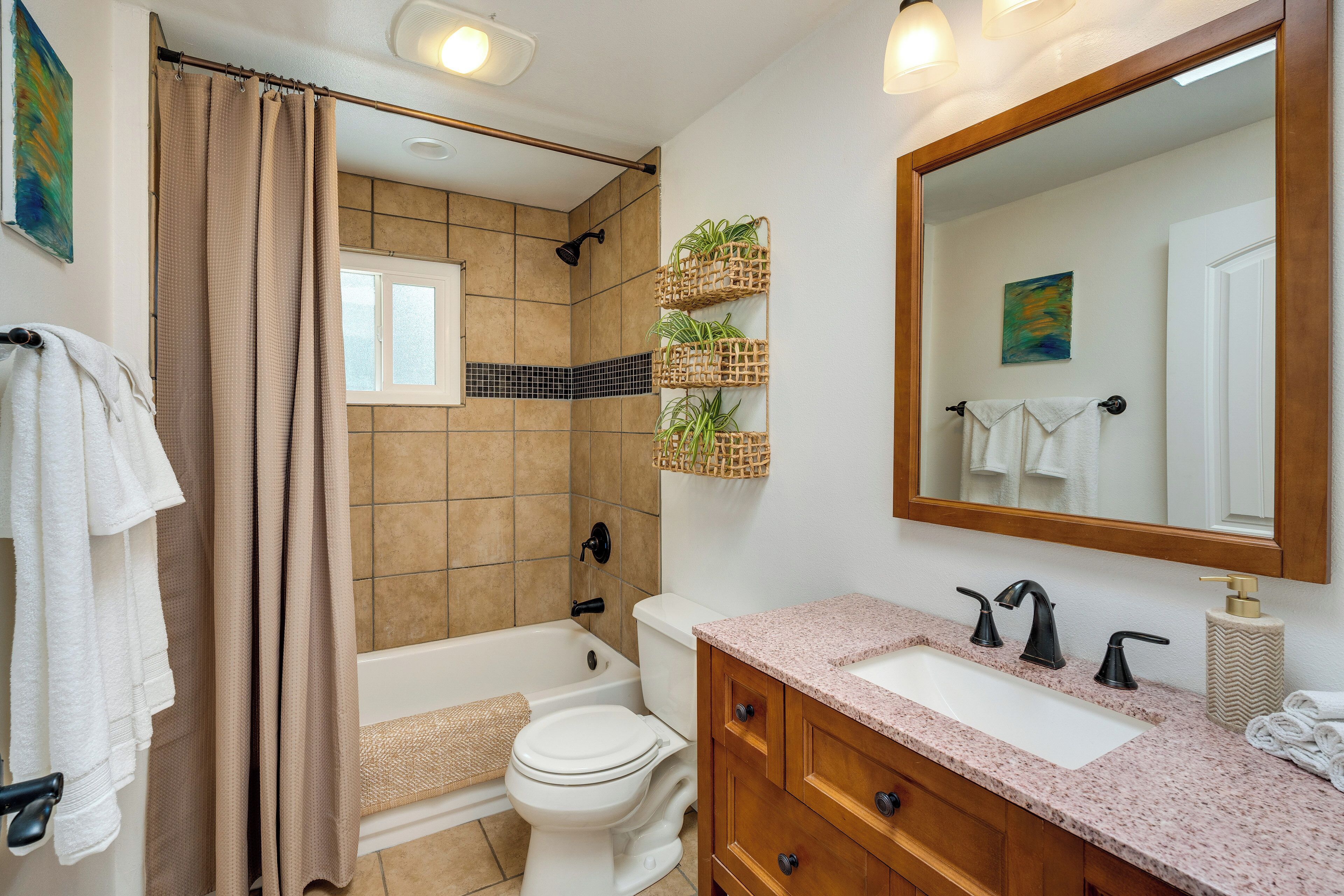 A bathroom with a bathtub, toilet, and sink. There are towels hanging on the wall and a mirror above the sink.