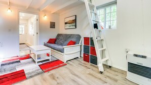 A compact living space with a loft bed, a sofa, a small table, and a red and black rug. - Charming Alaska Vacation Rental w/ Gas Grill! (Willow)
