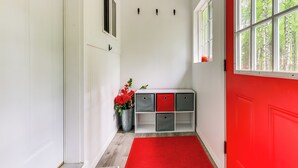 A hallway with a red door, a white wall, and a red rug. - Charming Alaska Vacation Rental w/ Gas Grill! (Willow)