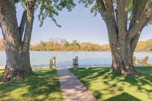 Un sendero que conduce a un lago, con árboles a ambos lados y una hilera de sillas Adirondack.