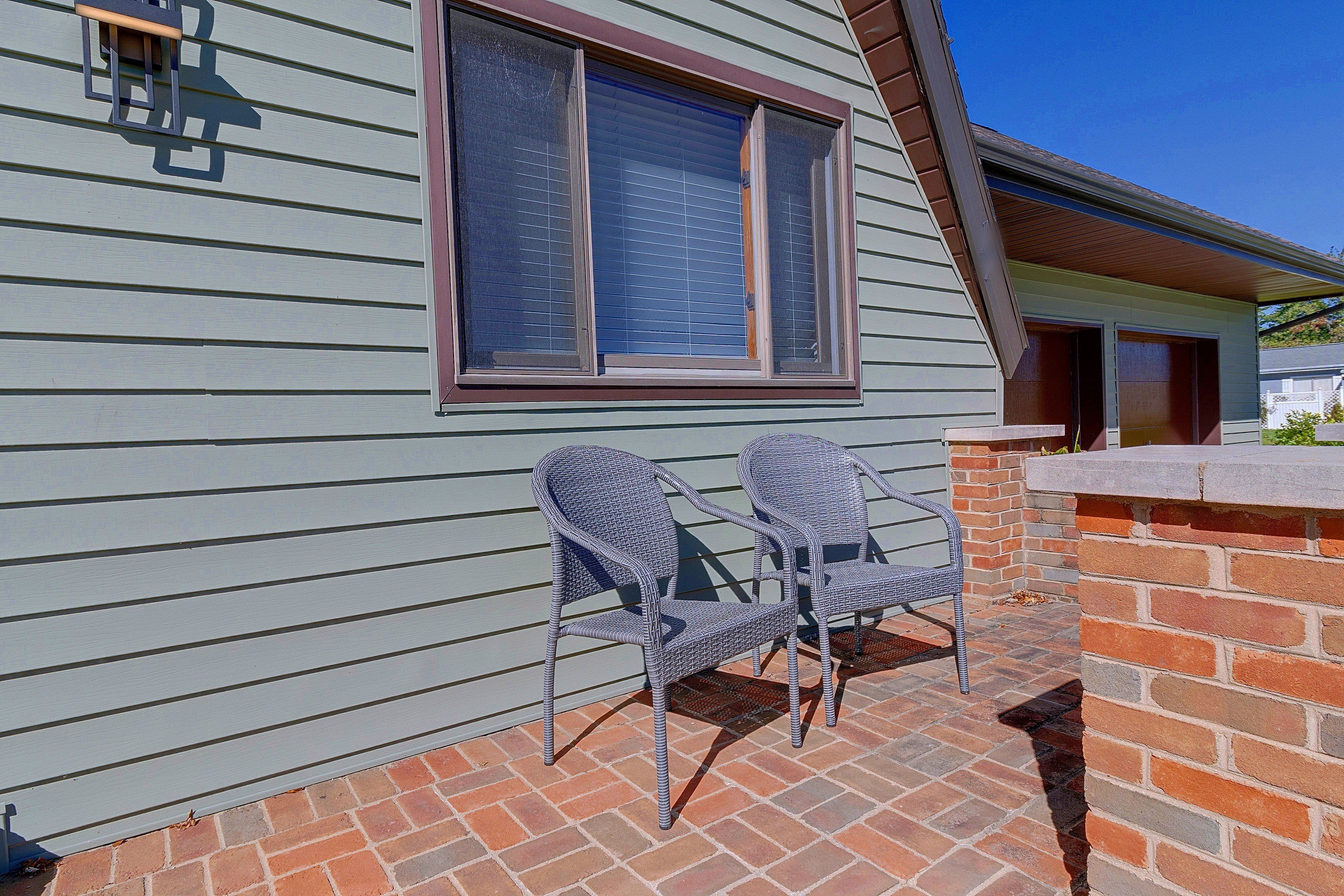 A patio with two wicker chairs and a brick wall.