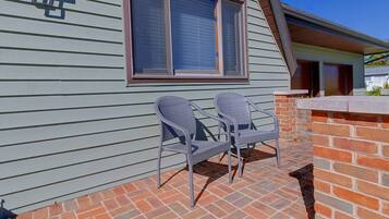 A patio with two wicker chairs and a brick wall.