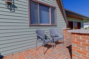 Une terrasse avec deux fauteuils en osier et un mur en briques.