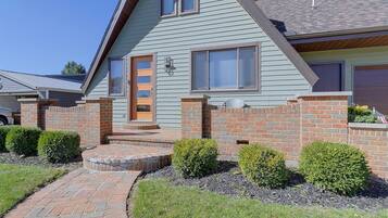 A two-story house with a brick exterior, a front porch, and a small garden area.