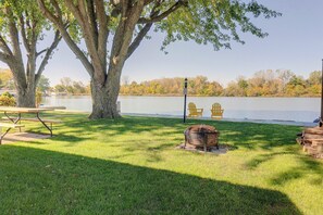 A lakeside park with picnic tables, a fire pit, and Adirondack chairs. - Lakefront St Marys Getaway w/ Boat Dock + Fire Pit (St. Marys)