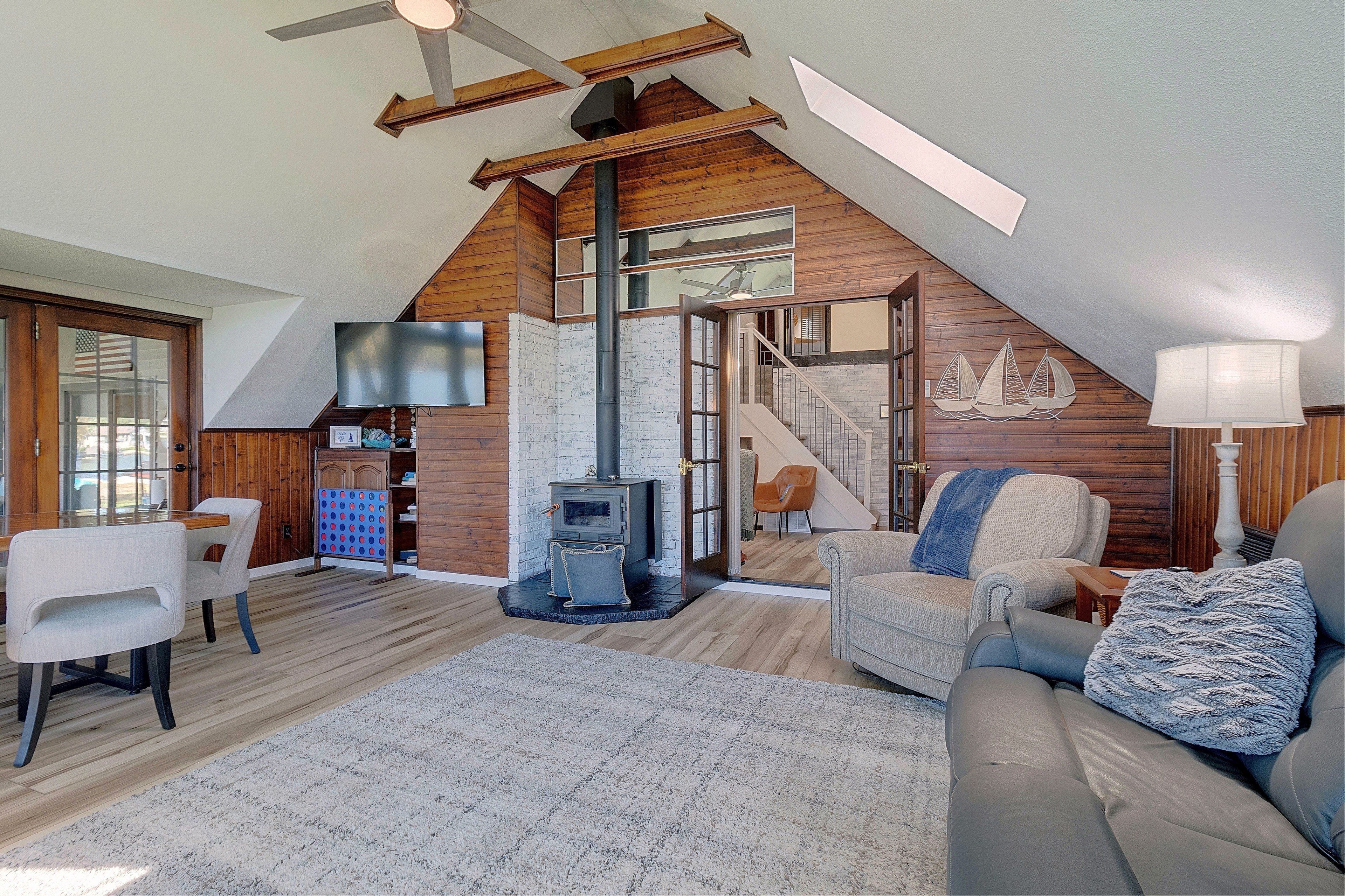 A loft-style living room with a high ceiling, a fireplace, a staircase, and a cozy seating area.