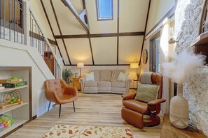 Un vaste espace de vie doté d’un haut plafond, d’un escalier, d’un ensemble de canapés et d’un fauteuil en cuir.
