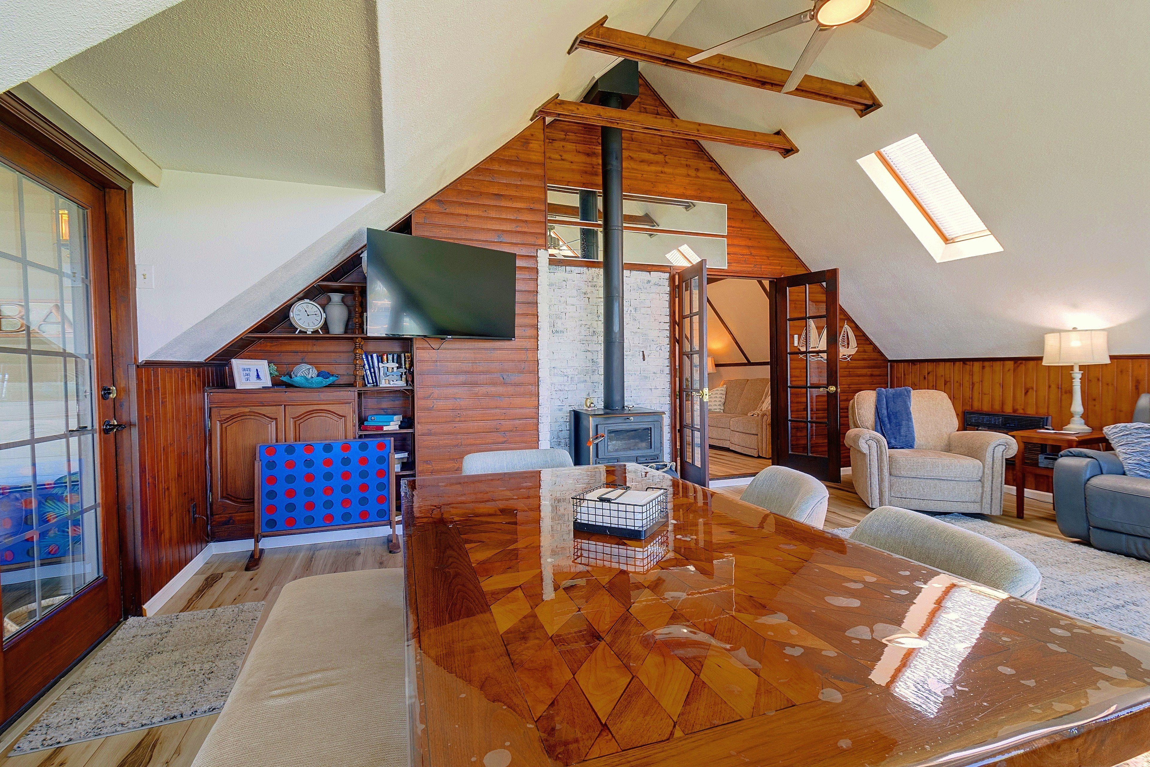 A spacious loft with a high ceiling, a wooden dining table, a fireplace, and a cozy seating area.