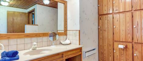 A bathroom with a wooden vanity, a large mirror, a sink, and a toilet.