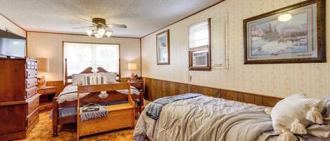 A bedroom with a bunk bed, a ceiling fan, a window with blinds, and a framed picture on the wall.