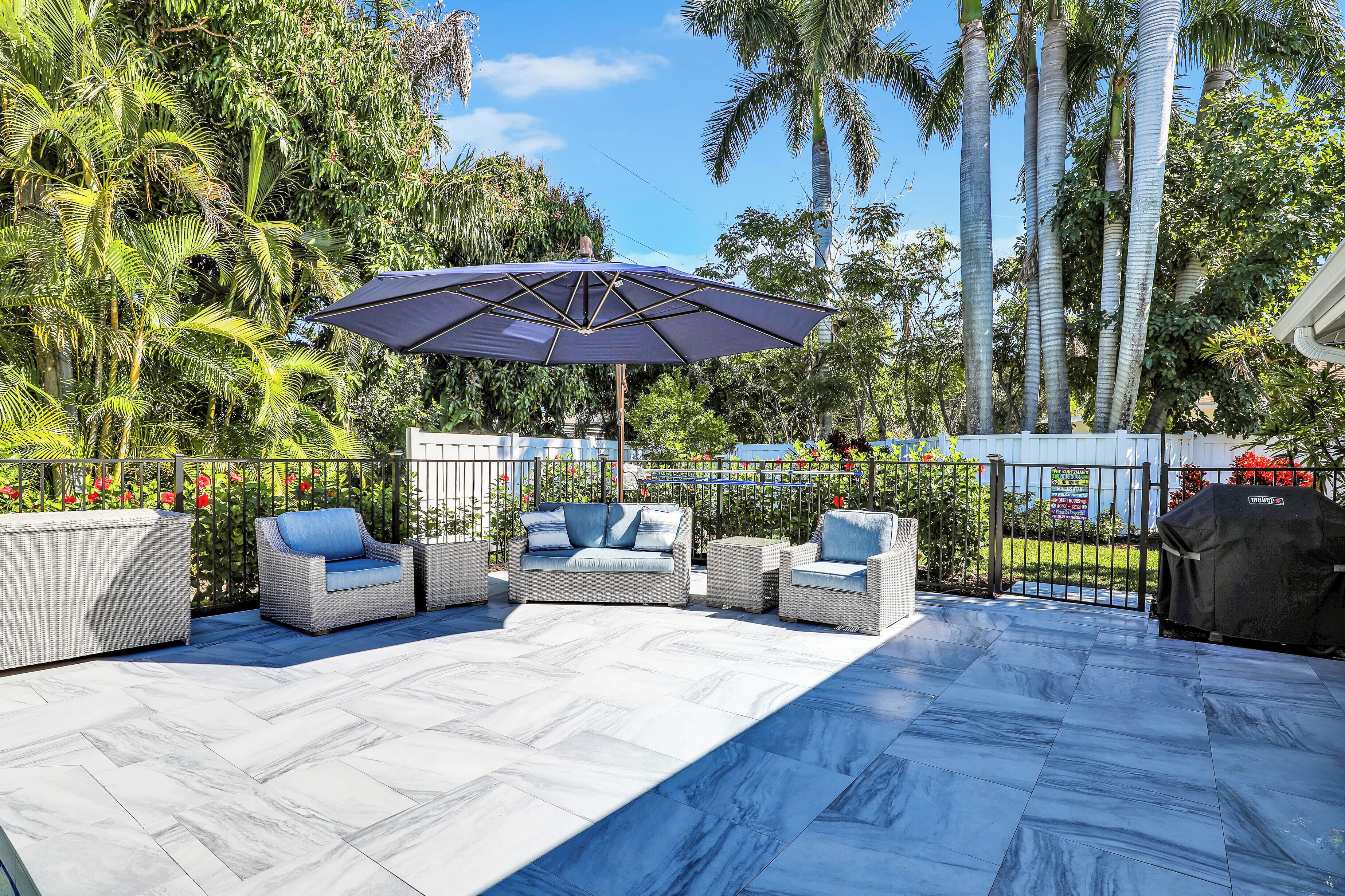 An outdoor patio with wicker furniture and a large umbrella.