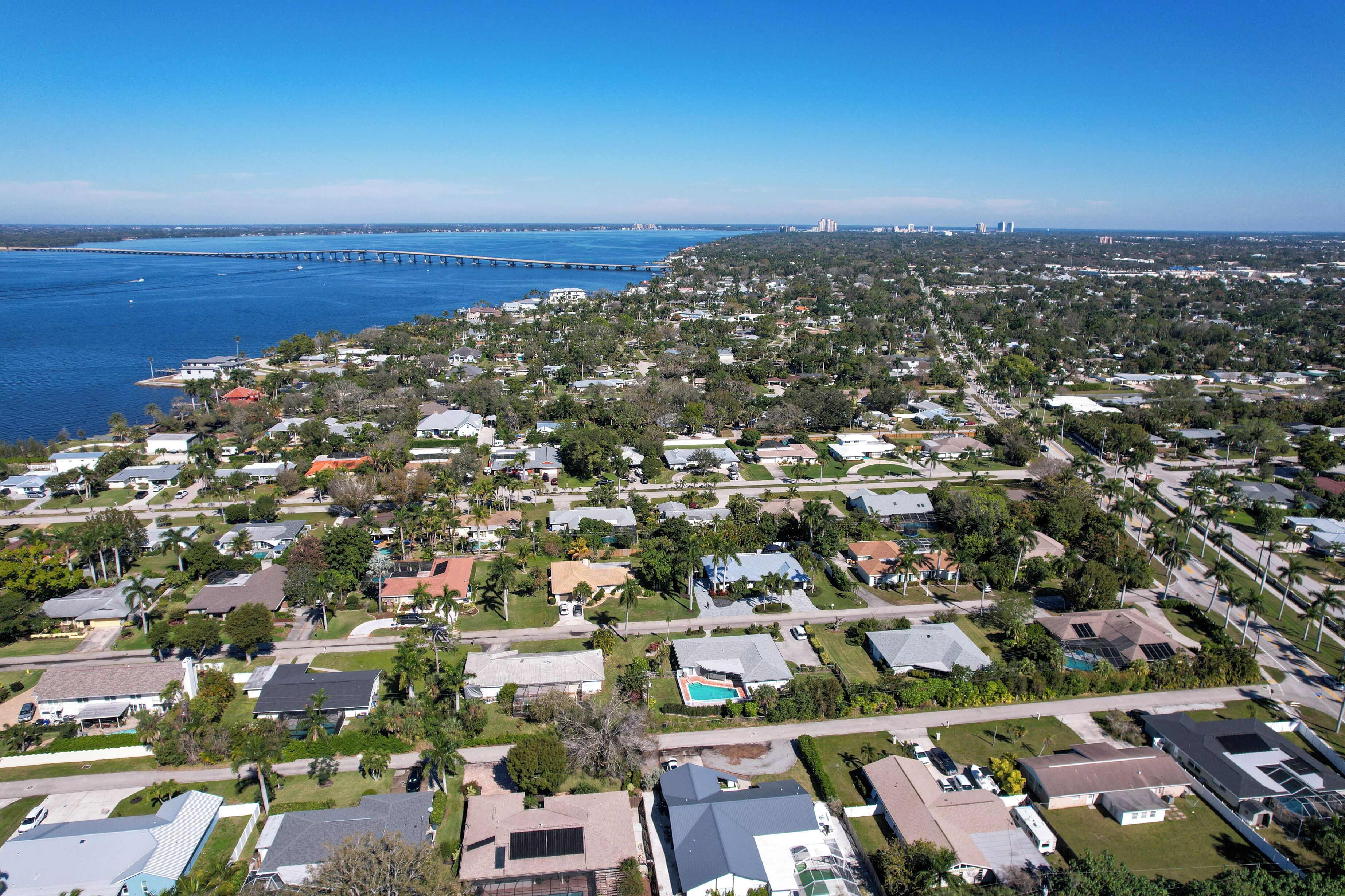 An aerial view of a residential area with houses, streets, and a bridge over water.