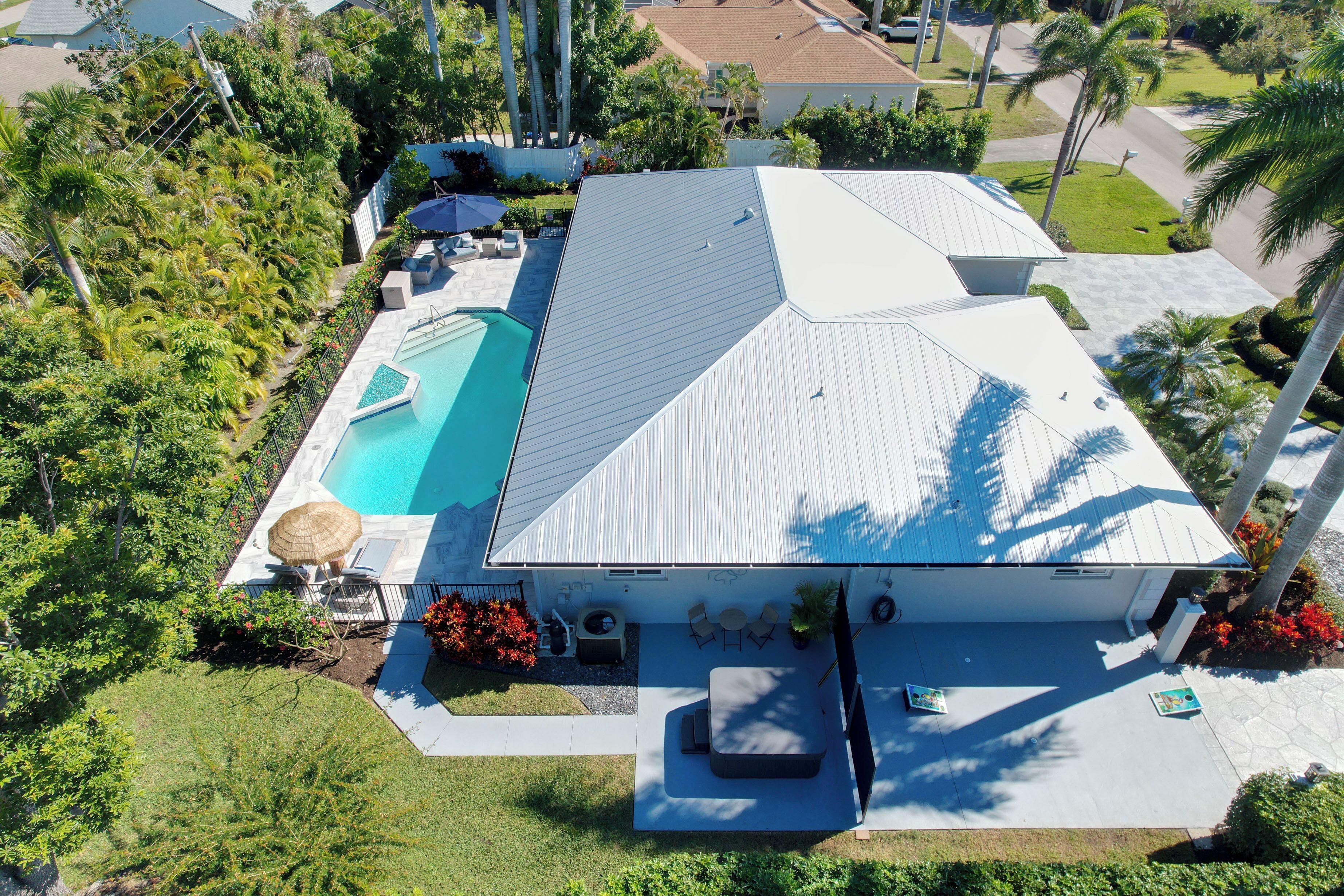 Eine Vogelperspektive eines Hauses mit Swimmingpool, Terrassenmöbeln und einer überdachten Außenlounge.