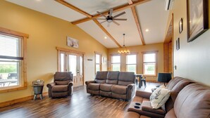 A spacious living room with a brown leather sofa, a recliner, and a dining area with a table and chairs. - Tranquil La Prairie Retreat w/ Patio & Fireplace! (La Prairie)