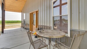 A covered patio with a round table and metal chairs, a wooden ceiling, and a view of a field. - Tranquil La Prairie Retreat w/ Patio & Fireplace! (La Prairie)
