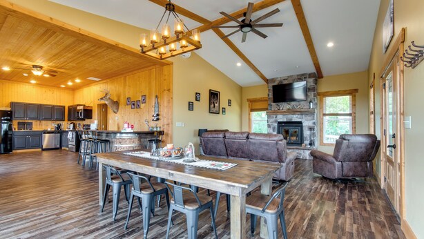 A spacious living area with a wooden dining table, leather seating, and a stone fireplace. - Tranquil La Prairie Retreat w/ Patio & Fireplace! (La Prairie)