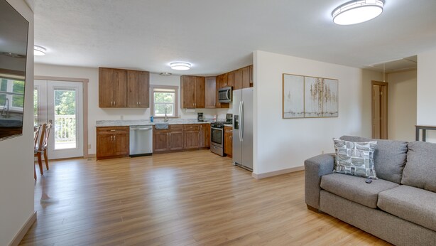 Ett rymligt kök med träskåp, ett kylskåp i rostfritt stål och en matplats med bord och stolar.