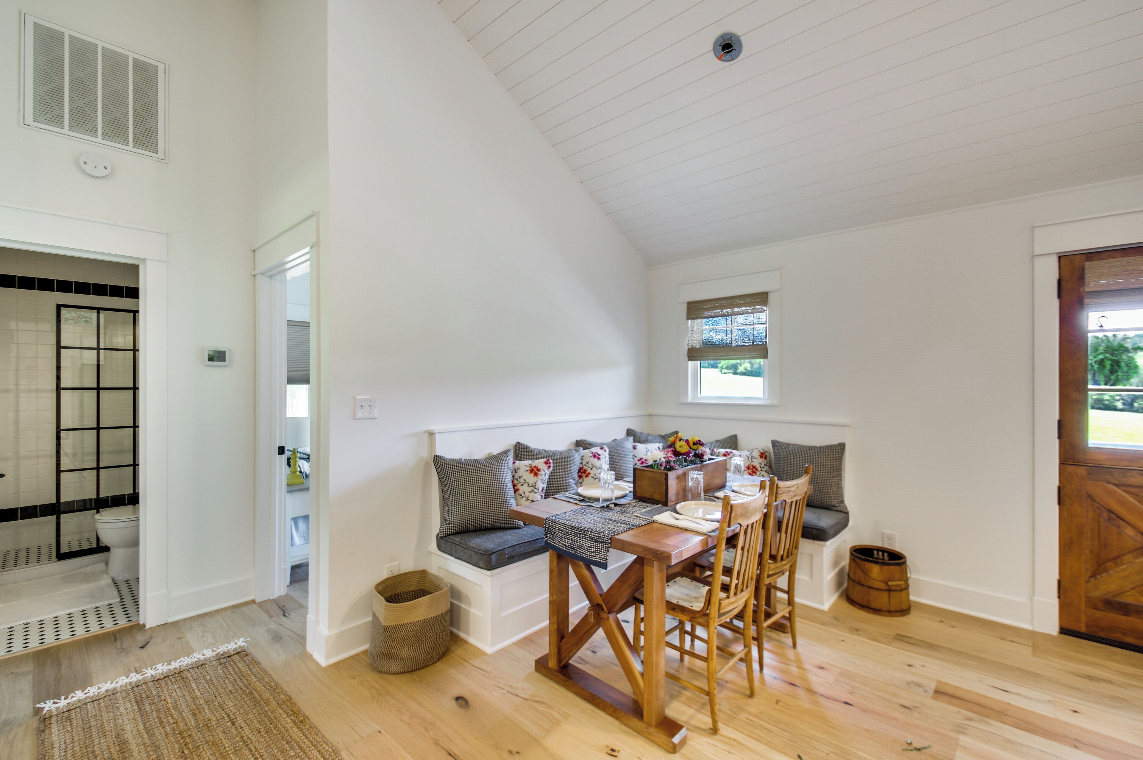 A dining area with a wooden table, chairs, and a bench with cushions.