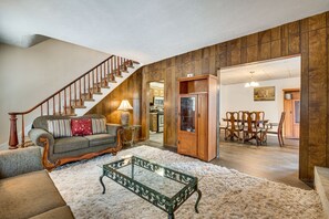 A spacious living room with a wooden staircase, a glass coffee table, a sofa, and a dining area. - Condo Rental w/ Pool Access ~ 11 Mi to Allentown! (Bath)