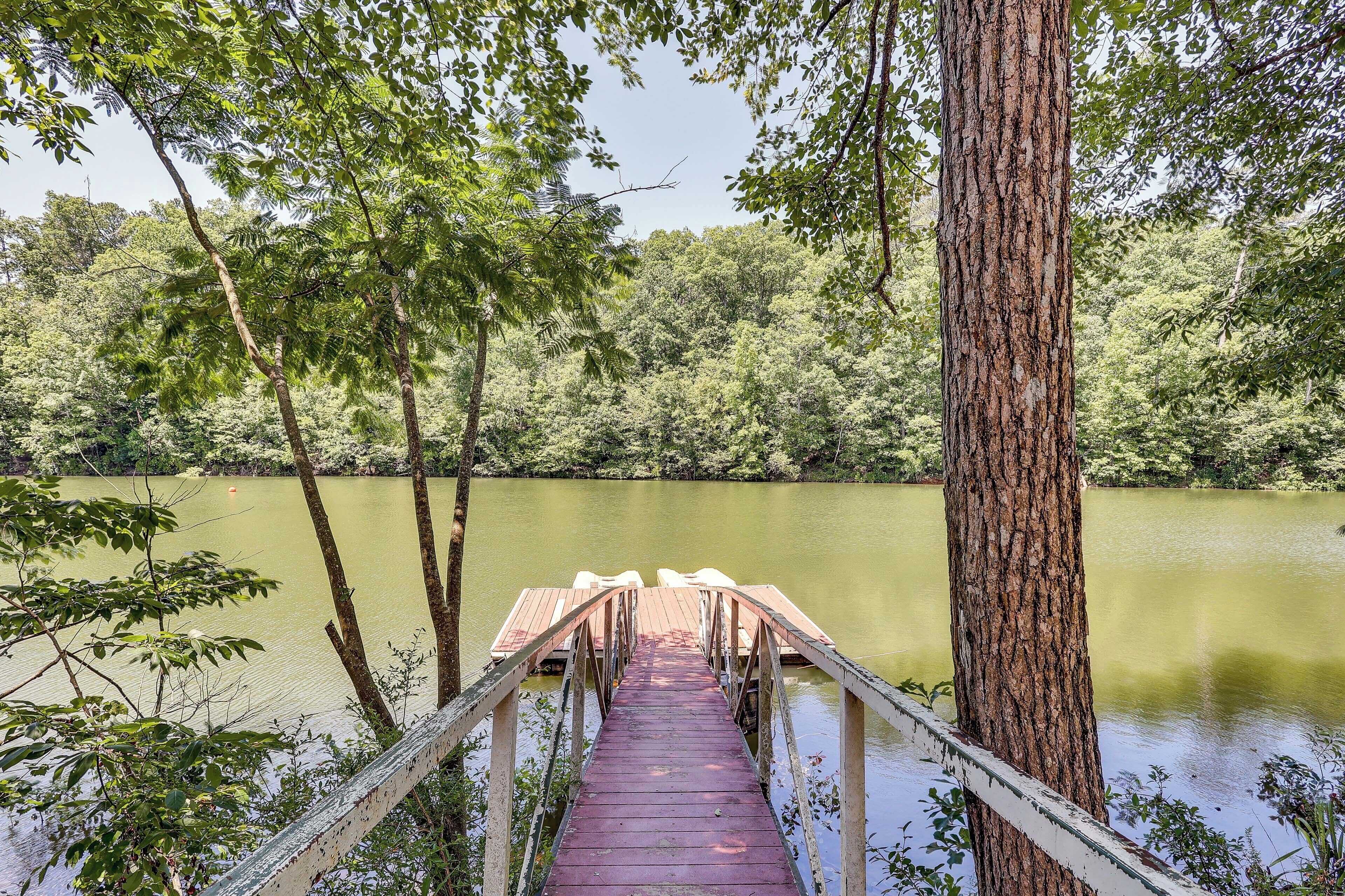 Un molo di legno che si estende su un lago tranquillo, circondato da alberi fitti.