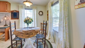 A dining area with a wooden table, chairs, a chandelier, and a window with curtains. - Sunny Florida Escape w/ Screened-in Patio & Grill! (Caryville)