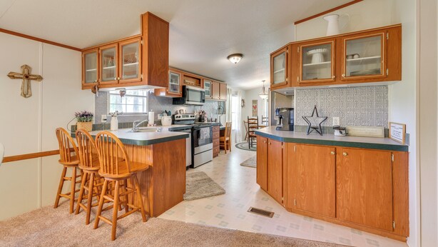 A kitchen with wooden cabinets, a central island with bar stools, a microwave, and a stove. - Sunny Florida Escape w/ Screened-in Patio & Grill! (Caryville)