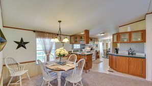 A spacious kitchen with wooden cabinets, a dining area with white chairs, and a central island. - Sunny Florida Escape w/ Screened-in Patio & Grill! (Caryville)