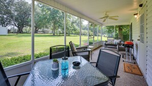 A covered patio with a glass table, chairs, and a view of a grassy yard. - Sunny Florida Escape w/ Screened-in Patio & Grill! (Caryville)