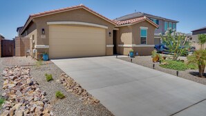 A residential house with a garage, a driveway, and a landscaped garden with rocks and small plants. - Tucson 4BR Retreat! Private Pool, Fire Pit! (Tucson)