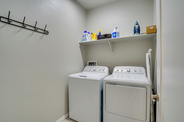 A laundry room with two white washing machines, a drying rack, and shelves with cleaning supplies. - Tucson 4BR Retreat! Private Pool, Fire Pit! (Tucson)