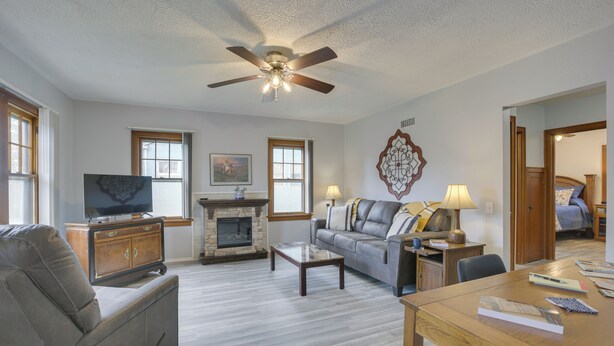 A living room with a fireplace, sofa, coffee table, and a television on a wooden cabinet. - Glendive Getaway w/ Yellowstone River Access! (Glendive)
