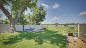 A backyard with a lawn, a tree, a swing set, and a fenced area. - Glendive Getaway w/ Yellowstone River Access! (Glendive)