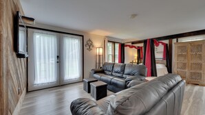 A modern living room with a leather sofa, a coffee table, and a sliding glass door leading to a balcony. - Pet-friendly Caneadea Retreat With Deck! (Belfast)