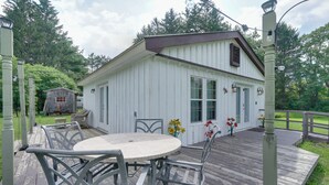A white wooden building with a porch, a table and chairs, and a small shed in the background. - Pet-friendly Caneadea Retreat With Deck! (Belfast)