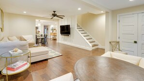 A spacious living room with a sofa, a coffee table, a dining table, and a TV mounted on the wall. - Upper Black Eddy Home w/ Delaware River Access! (Upper Black Eddy)