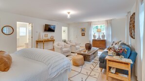 A spacious living room with a large bed, a sofa, a coffee table, and a television. - Idyllic Cave Spring Studio w/ Patio & Fire Pit! (Roanoke)