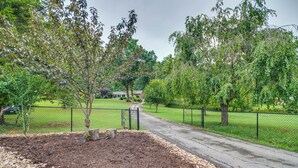 A paved pathway leading to a building with a fenced yard and trees. - Idyllic Cave Spring Studio w/ Patio & Fire Pit! (Roanoke)